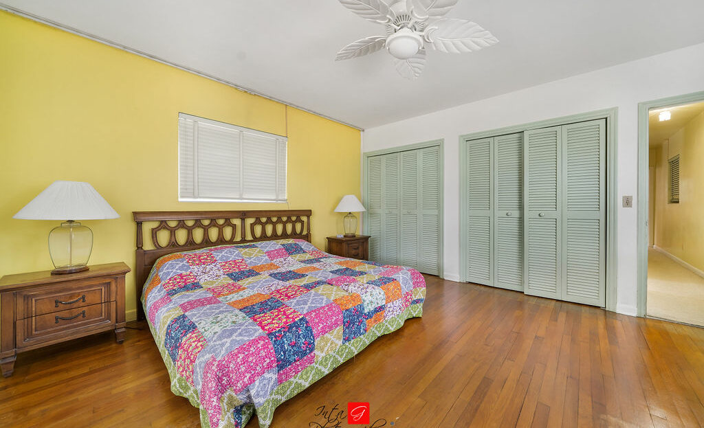 A bedroom with yellow walls and hardwood floors.