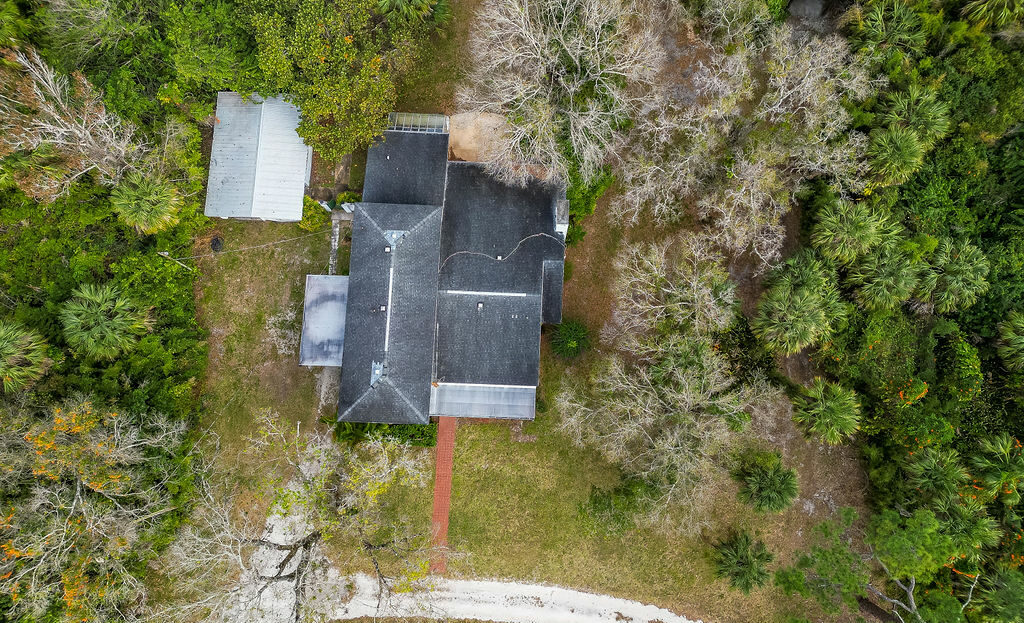 An aerial view of a house in the woods.