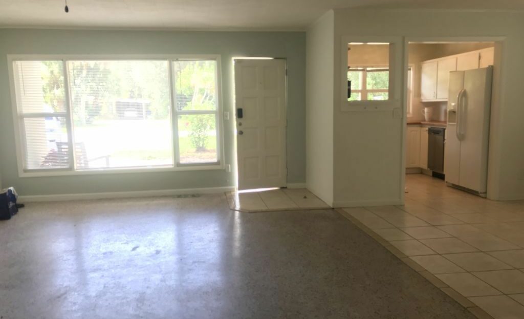 An empty living room with tile floors and a ceiling fan.